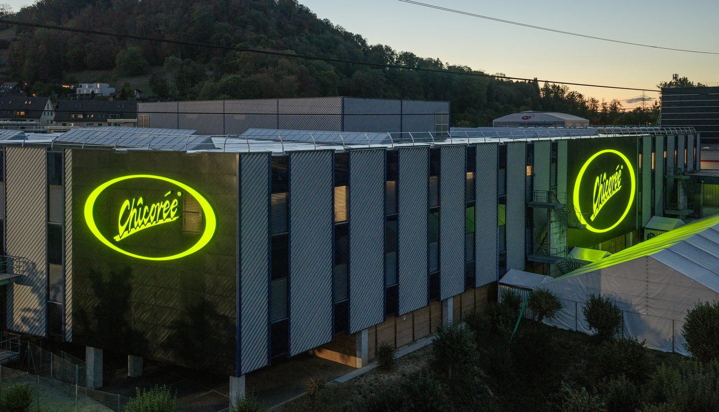 Huge illuminated “Chicorée” logos on two sides of the central warehouse in Brunegg.