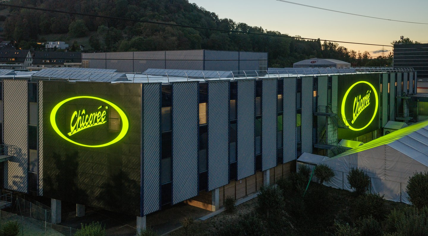 D'immenses logos lumineux « Chicorée » sur deux côtés de la façade de l'entrepôt central de Brunegg.