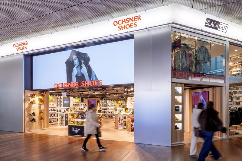Grosser LED-Screen mit 3D-Content und hellem Leuchtschriftzug vor der Ochsner Shoes-Filiale im Tivoli.