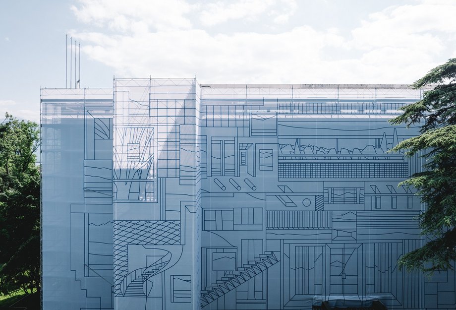 Frontalansicht eines Gebäudes, das vollständig mit einer hellen Gerüstverkleidung eingekleidet ist; auf der riesigen Plane sind feine, blaue Linien als architektonische Zeichnung über die ganze Fassade gedruckt. Das Bild zeigt die Grossformat-Umsetzung und Baugerüst-Einkleidung für den Hauptsitz der Vaudoise Versicherungen in Lausanne – das Kunstprojekt «On and Around» von Nigel Peake, umgesetzt von Richnerstutz.