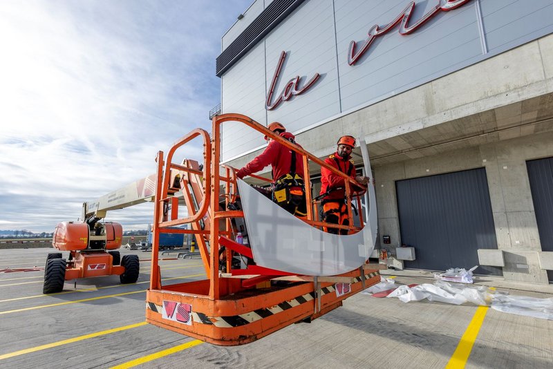 Installers from Richnerstutz on an aerial work platform with an illuminated letter segment of the facade signage for Bell Switzerland.