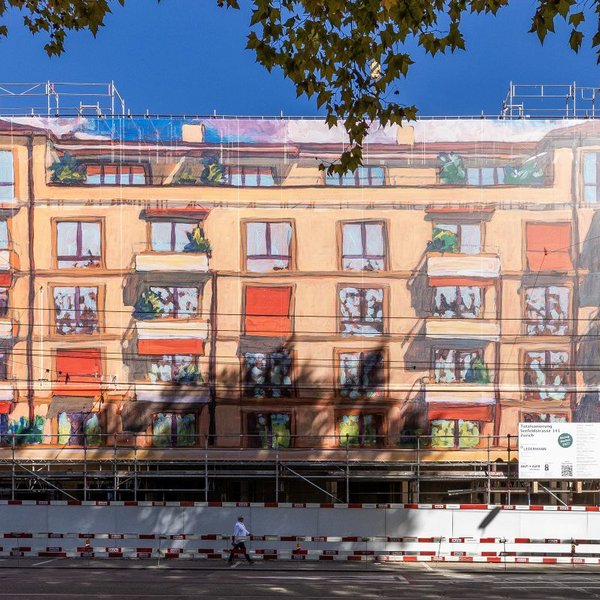 A close-up frontal view of an apartment building covered in scaffolding: A large scaffolding structure is draped with a printed mesh tarp that resembles facade art and traces the building’s facade as a colorful image. The large-scale scaffolding design was produced by Richnerstutz as a large-format print—based on an acrylic painting by Michele Bordoni, reproduced in high resolution by undknup AG, commissioned by Urs Ledermann.
