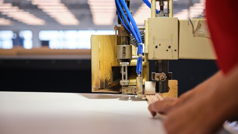 Une collaboratrice perce des œillets dans une grande bâche pour l’ESAF 2025.